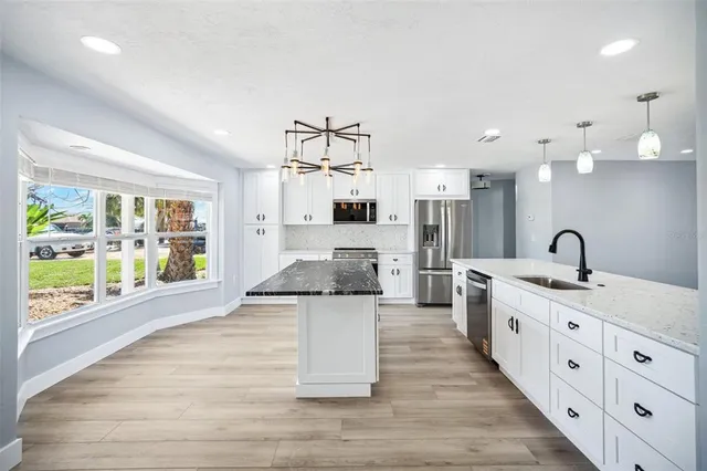 a large kitchen with stainless steel appliances kitchen island a large counter top and a wooden floors
