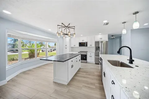 a large kitchen with granite countertop a stove a sink a refrigerator and window