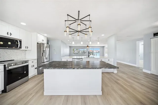 a large kitchen with stainless steel appliances granite countertop a sink a stove and a wooden floors