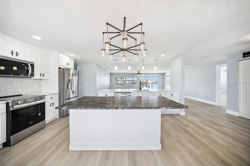 6410 3rd Palm Point St. Pete Beach, FL 33706 - Photo 10 of 54 a large kitchen with stainless steel appliances granite countertop a sink a stove and a wooden floors