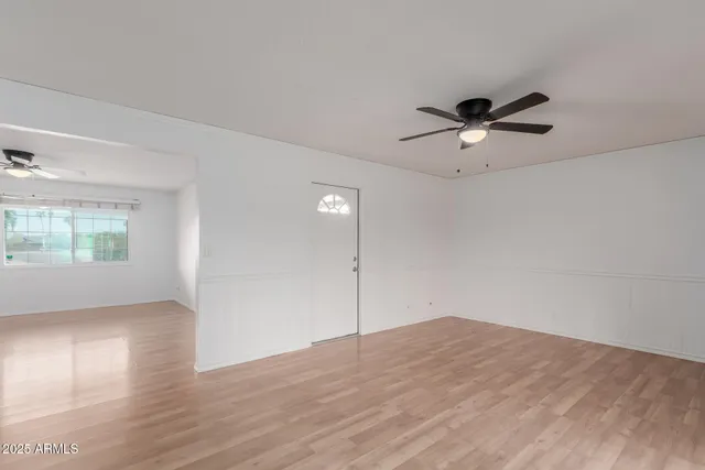 an empty room with wooden floor and windows