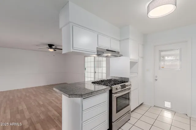 a kitchen with granite countertop a sink stove and cabinets