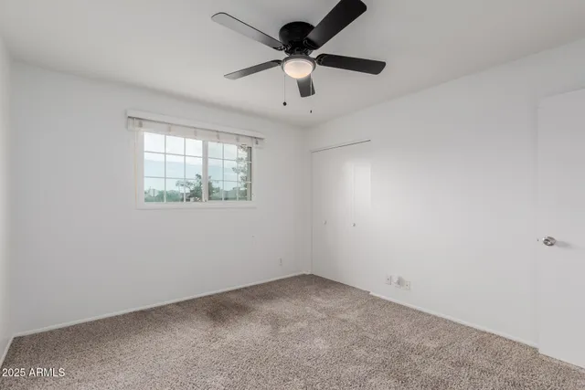 an empty room with a window and a ceiling fan