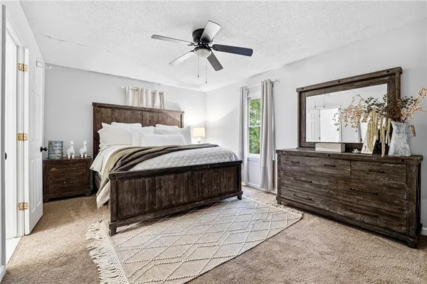 a bedroom with a bed a dresser and potted plant