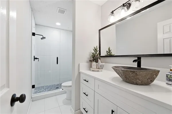 a bathroom with a granite countertop sink a toilet and shower