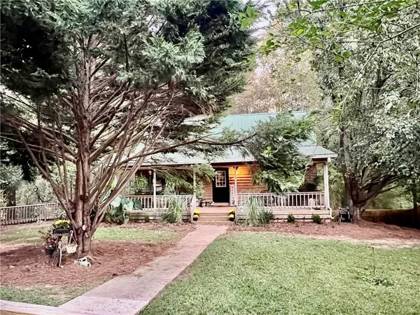 a front view of a building with a garden and trees