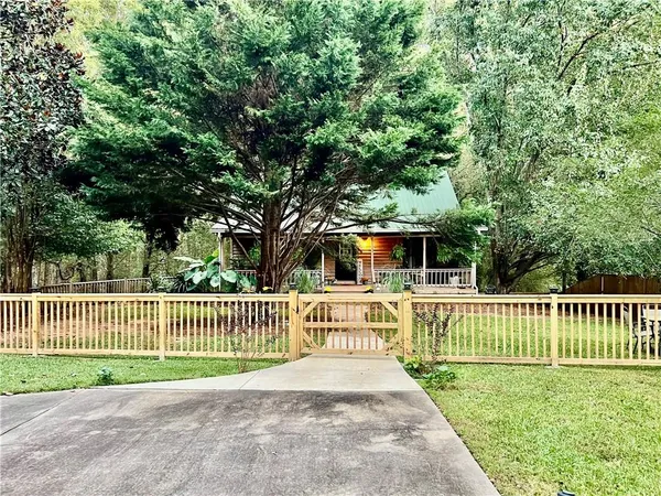a view of a house with a small yard and a large tree