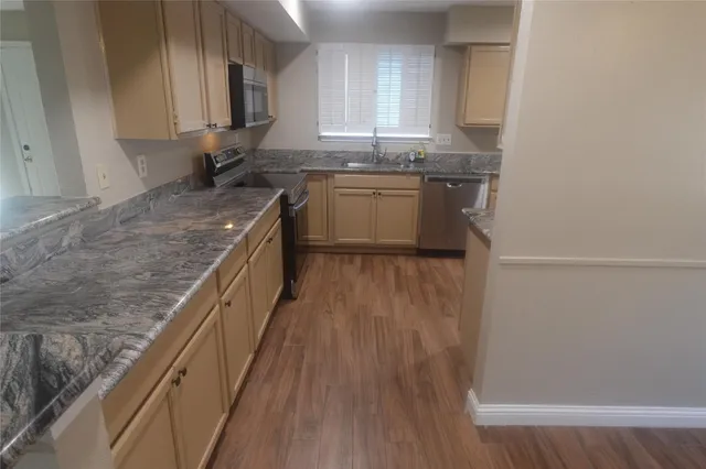 a kitchen with granite countertop a sink a counter top space and cabinets
