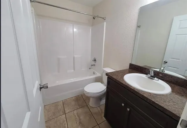 a bathroom with a granite countertop sink toilet mirror vanity and bathtub