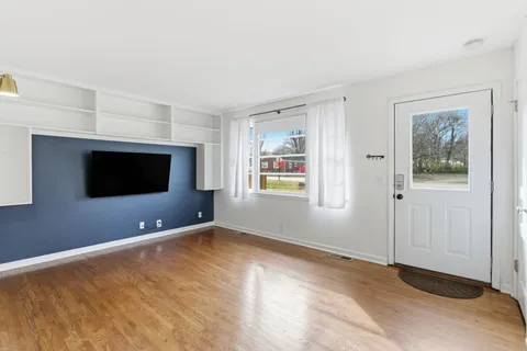 a view of an empty room with a window and a kitchen