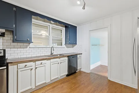 a kitchen with stainless steel appliances granite countertop a sink and cabinets with wooden floor