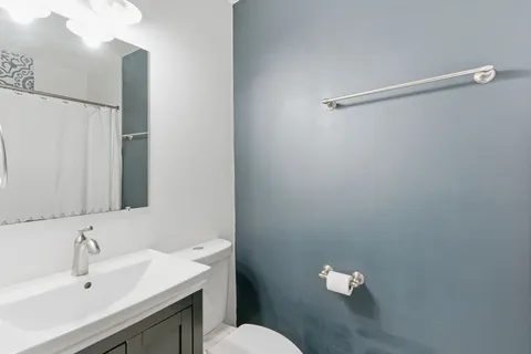 a bathroom with a sink mirror and a toilet
