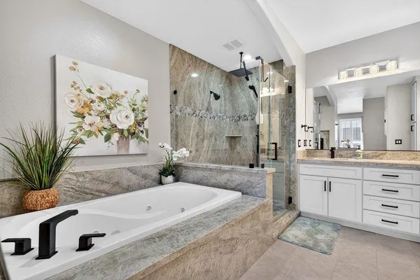 a spacious bathroom with a granite countertop tub sink a mirror a vanity and shower
