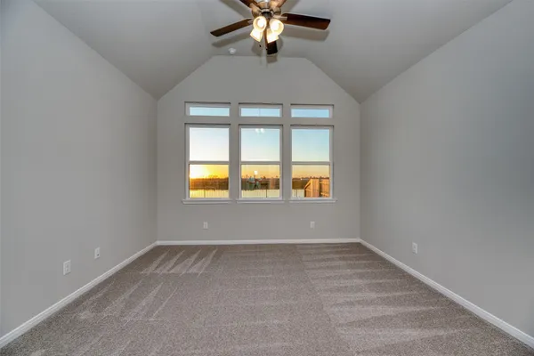 an empty room with chandelier fan and windows
