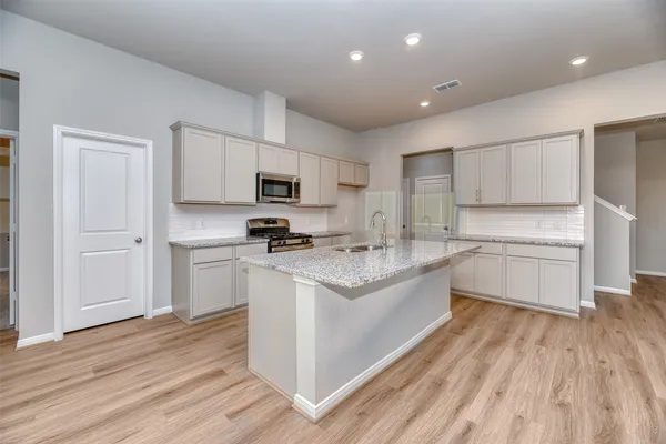 a kitchen with a sink wooden floor and stainless steel appliances