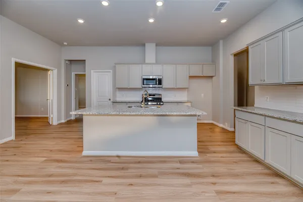 a large kitchen with stainless steel appliances granite countertop a stove a sink and a refrigerator