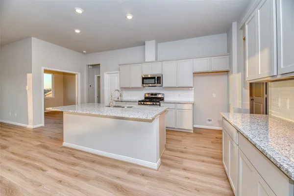 a kitchen with granite countertop a sink stove and refrigerator