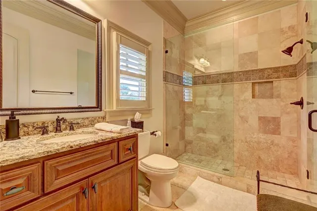 a bathroom with a granite countertop sink toilet mirror and shower