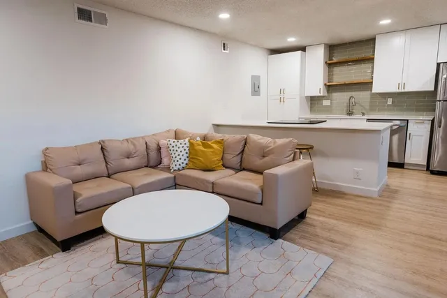 a living room with a couch and a view of kitchen appliances