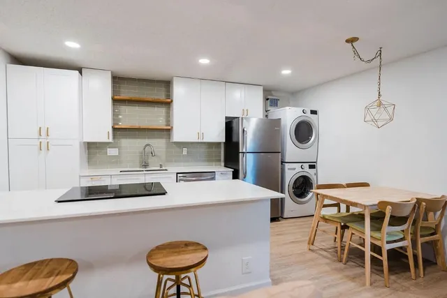 a kitchen with stainless steel appliances a stove a refrigerator a sink a dining table and chairs