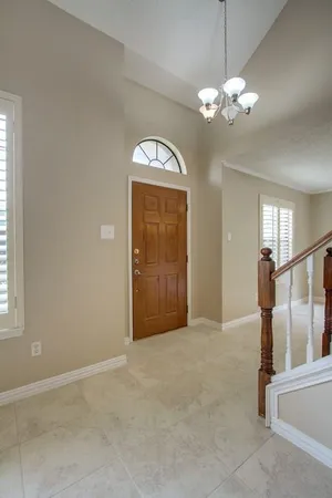 an empty room with chandelier fan and windows