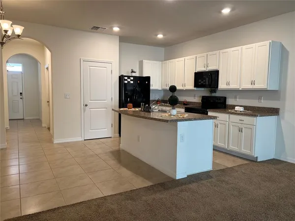 a kitchen with kitchen island granite countertop stainless steel appliances a sink stove refrigerator and cabinets