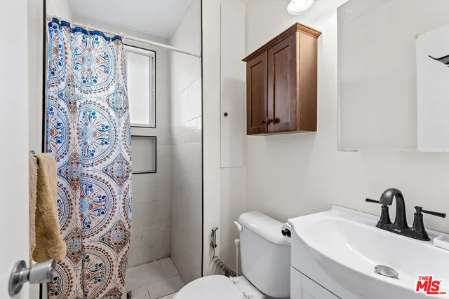 a bathroom with a toilet sink and shower curtain
