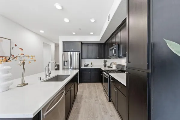 a kitchen with kitchen island granite countertop a sink stainless steel appliances and cabinets