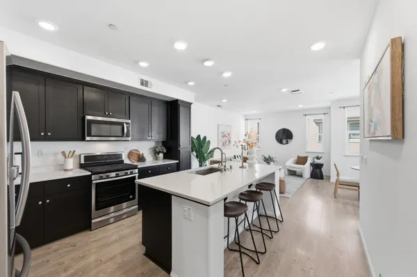 a kitchen with stainless steel appliances a stove a sink a microwave a refrigerator and cabinets