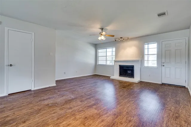 an empty room with wooden floor fireplace and windows