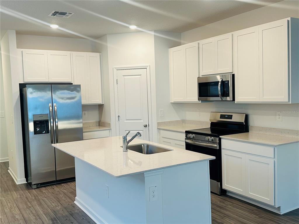 1139 Northwest 44th Court Road Ocala, FL 34482 - Photo 12 of 36 a kitchen with kitchen island a sink dishwasher a stove and a refrigerator with wooden floor