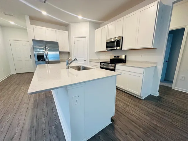 a kitchen with wooden floor a sink a stove and microwave