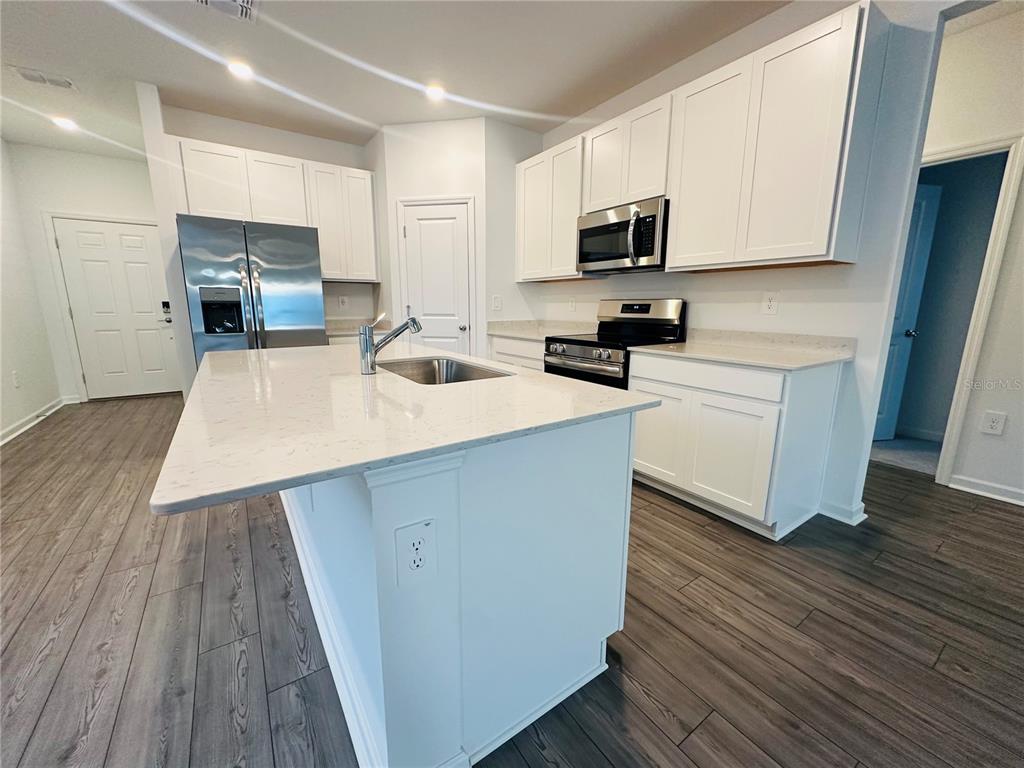 1139 Northwest 44th Court Road Ocala, FL 34482 - Photo 14 of 36 a kitchen with wooden floor a sink a stove and microwave
