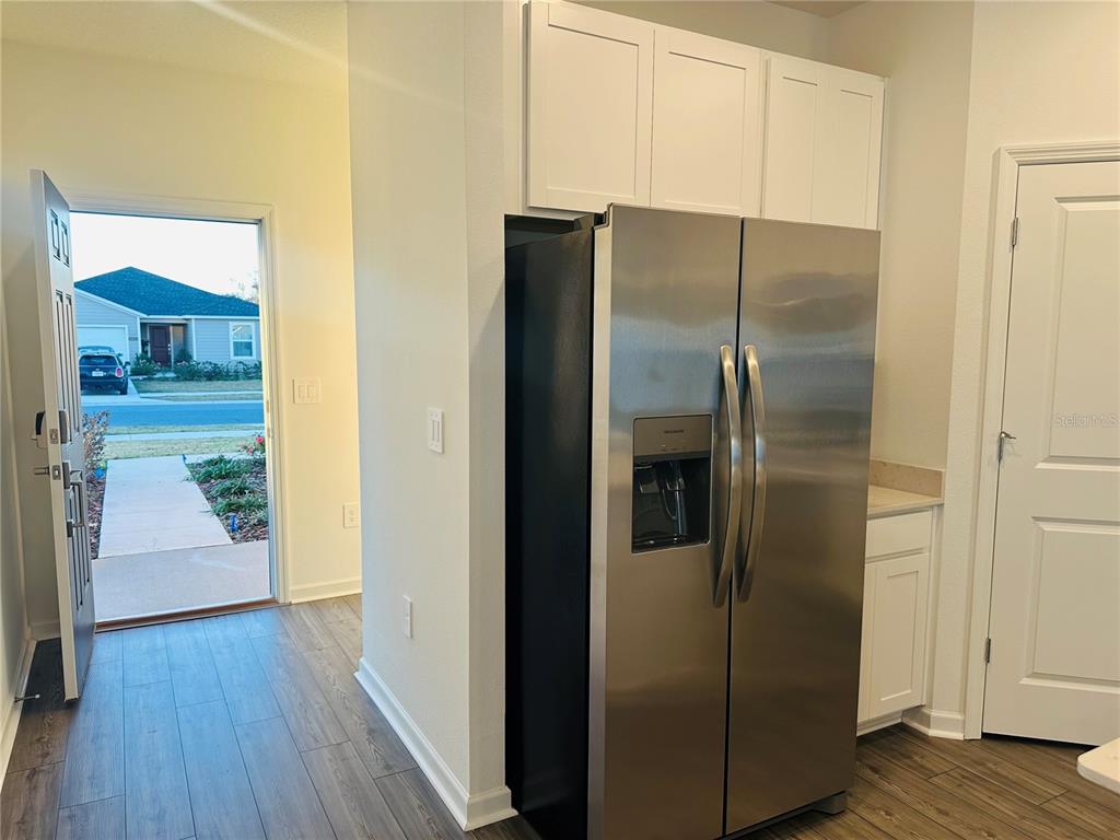 1139 Northwest 44th Court Road Ocala, FL 34482 - Photo 8 of 36 a view of a refrigerator in kitchen and an empty room with wooden floor
