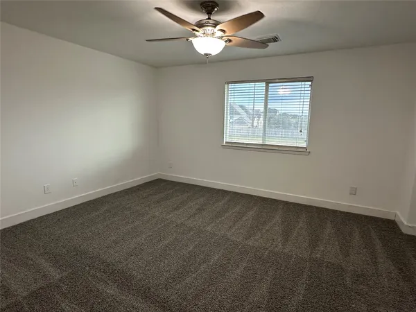an empty room with a window and a fan