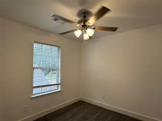 an empty room with a window and a fan