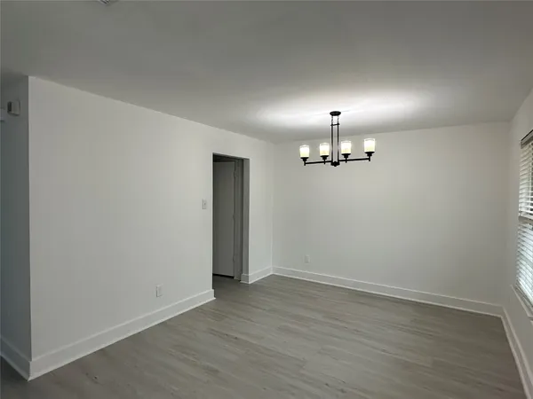 an empty room with wooden floor ceiling fan and windows