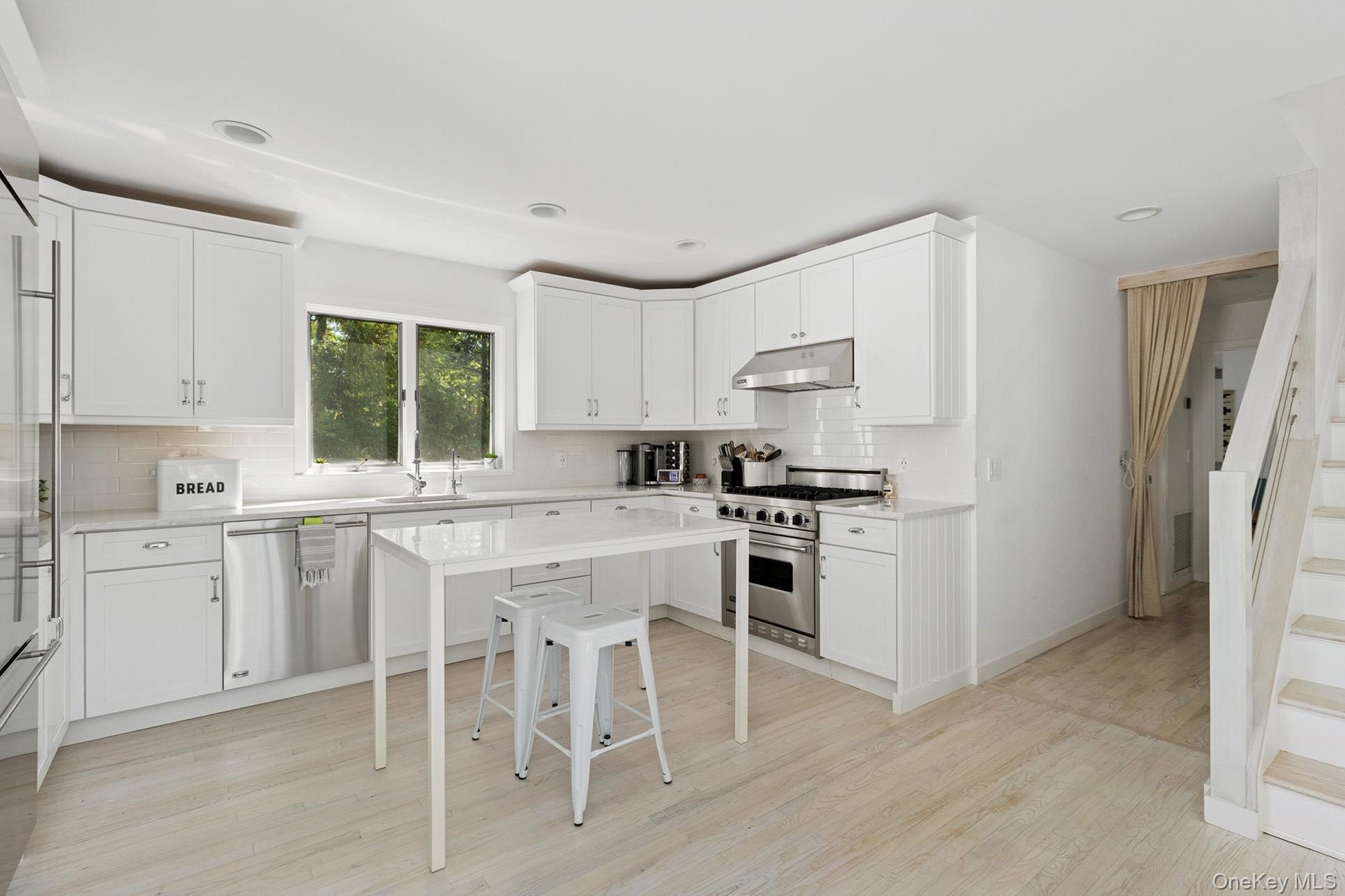 28 Ridge Road Wainscott, NY 11937 - Photo 28 of 40 a kitchen with white cabinets and white appliances