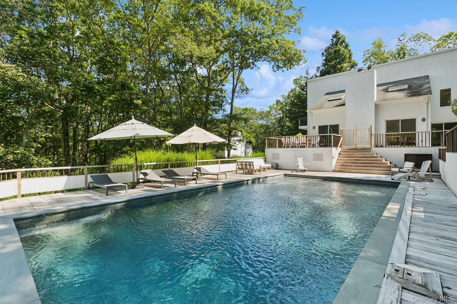 28 Ridge Road Wainscott, NY 11937 - Photo 4 of 40 a view of swimming pool with outdoor seating and trees in the background