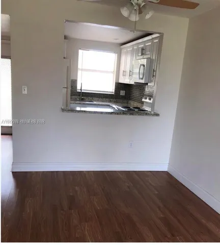 a view of a room with wooden floor and a ceiling fan