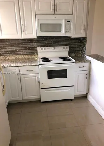 a kitchen with granite countertop white cabinets and white appliances