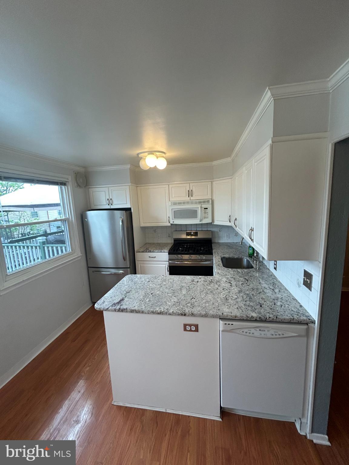 10830 Perrin Road Philadelphia, PA 19154 - Photo 3 of 25 a kitchen with stainless steel appliances granite countertop a sink a stove a refrigerator and a granite counter tops with wooden floors