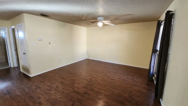 an empty room with wooden floor and fan