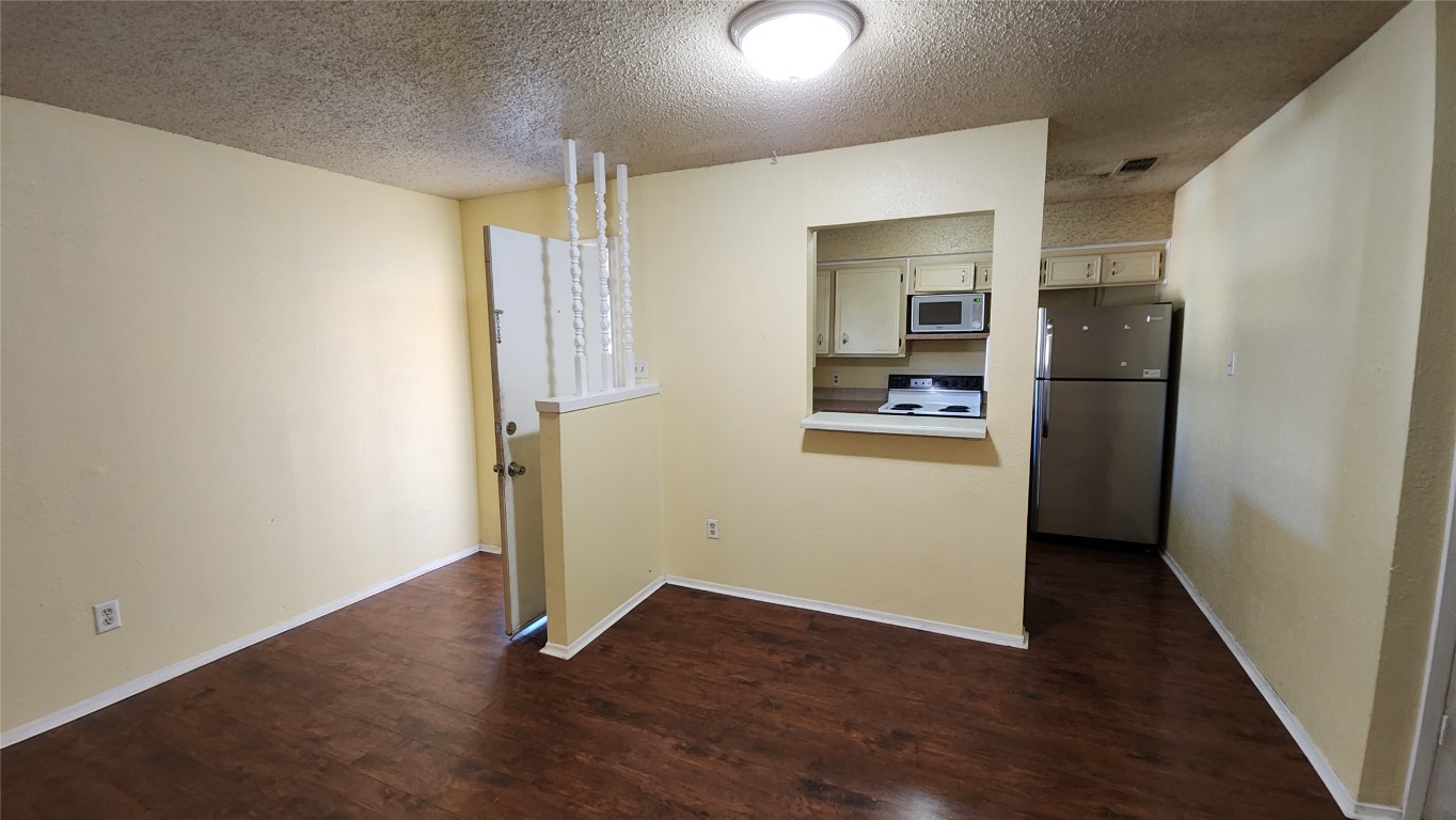 208 Vanderveer, Unit 4 Burnet, TX 78611 - Photo 5 of 13 an empty room with wooden floor and a kitchen