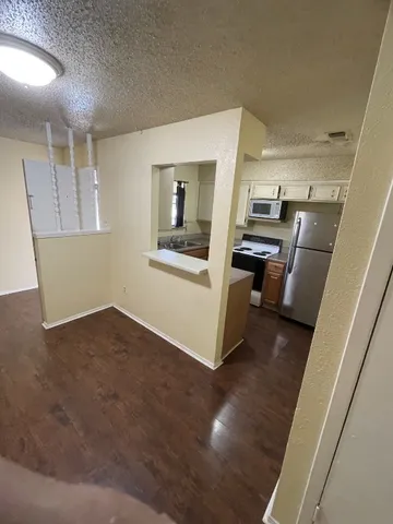 a view of kitchen and empty room with wooden floor
