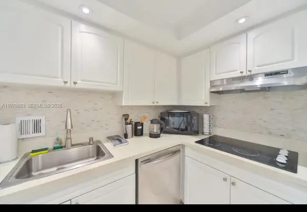 a kitchen with stainless steel appliances granite countertop a sink a stove and white cabinets