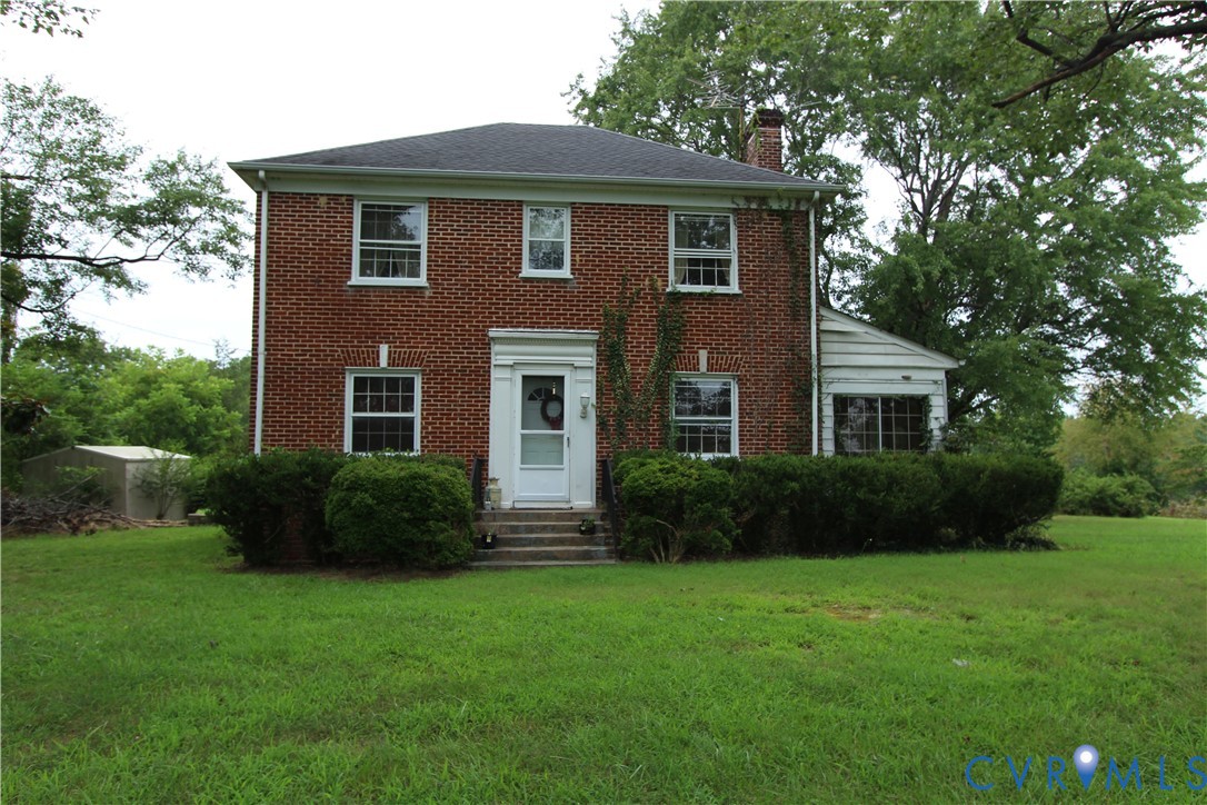 a front view of a house with a yard and green space