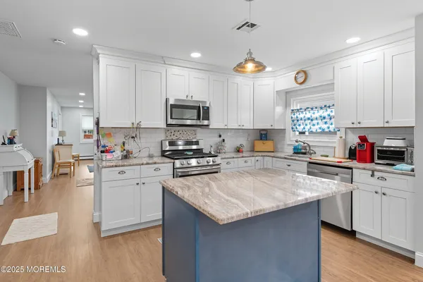 a kitchen with kitchen island granite countertop a sink cabinets and stainless steel appliances