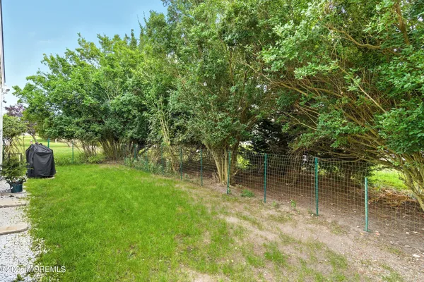 a backyard of a house with lots of plants and large tree