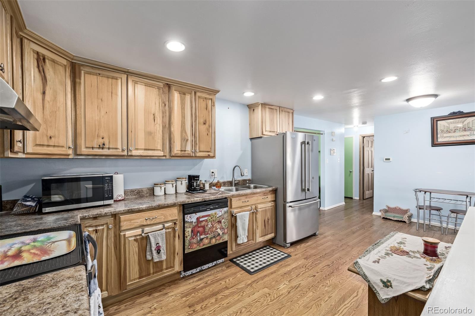 8227 Depew Way Arvada, CO 80003 - Photo 14 of 31 a kitchen with stainless steel appliances granite countertop a stove a sink dishwasher a refrigerator and cabinets with wooden floor